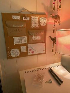 a white desk topped with lots of writing and papers next to a wall mounted memo board