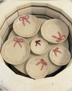 six plates with pink bows on them sitting in a bowl