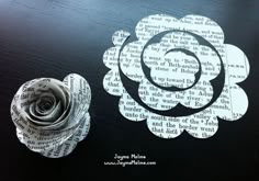 a paper flower sitting on top of a table next to a piece of book pages