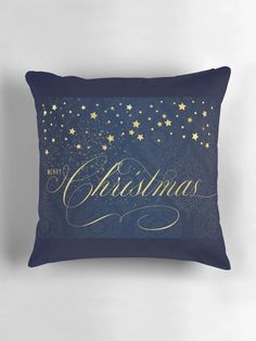 a blue pillow with gold stars and the words christmas written in cursive writing