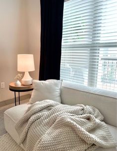 a white couch sitting in front of a window with a blanket on top of it