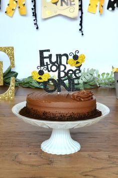 a chocolate cake on a white pedestal with the word fun for one written on it