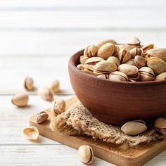 a wooden bowl filled with nuts on top of a cutting board