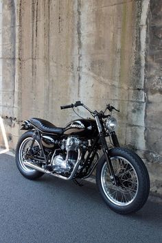 a black motorcycle parked in front of a stone wall