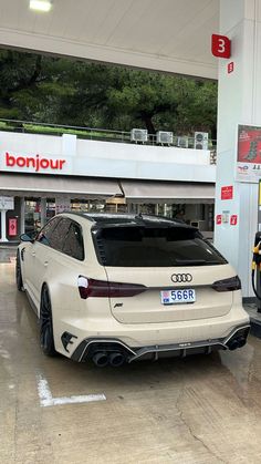 a white car parked in front of a gas station