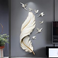 there is a wall sculpture made out of paper birds and feathers on the wall in this living room