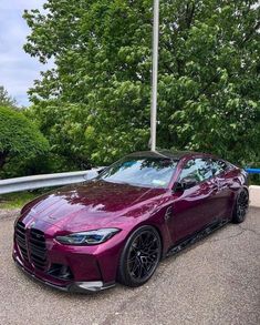 a purple sports car parked on the side of a road next to some green trees