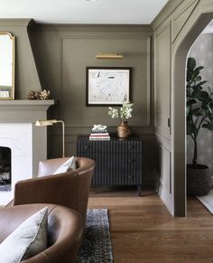 a living room filled with furniture and a fire place in front of a mirror on the wall