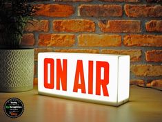 an on air sign sitting on top of a table next to a potted plant