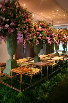 a long table covered in lots of flowers next to tall vases filled with flowers