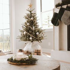 a living room with a christmas tree in the corner and presents on the coffee table