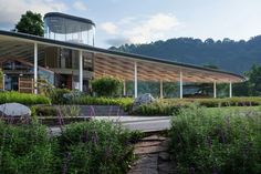 a large building with lots of plants in front of it and mountains in the background