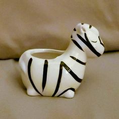 a ceramic zebra planter sitting on top of a bed next to a brown sheet