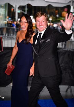 a man in a tuxedo and woman in a blue dress at an event