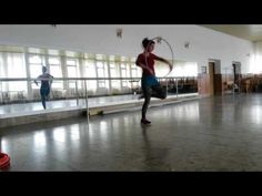 a woman is dancing with a hoop in the middle of an empty room while another person watches