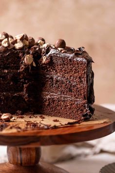 a chocolate cake on a wooden stand with one slice cut out and the rest half eaten