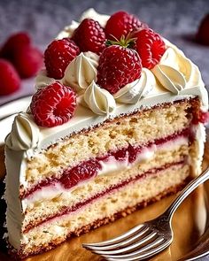 a piece of cake with white frosting and raspberries on top is sitting on a plate next to a fork