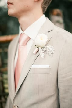 a man in a gray suit with a pink tie and flower boutonniere