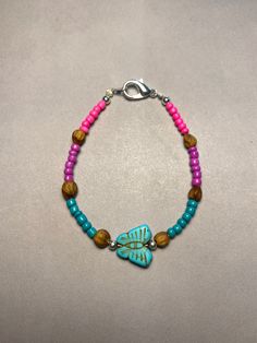 a blue and pink beaded bracelet with a turquoise butterfly charm on the end of it