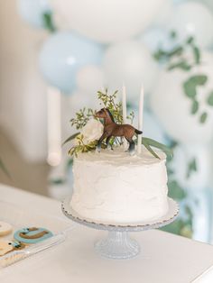 a white cake topped with a horse on top of a table