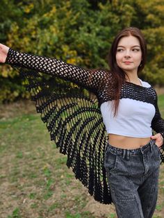 a woman in jeans and a crop top with wings on her shoulders is posing for the camera