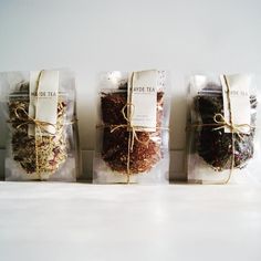 three bags filled with different types of tea sitting on top of a white counter next to each other