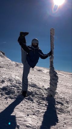 a man standing on top of a snow covered slope next to a tall ice sculpture