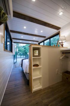 a bedroom with white walls and wood flooring next to a bed in a room