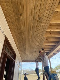 two men are working on the roof of a building that is being built with wood planks