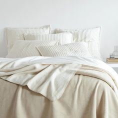 an unmade bed with white sheets and pillows