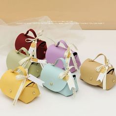 four small purses with bows and ribbons on the handles, all in different colors