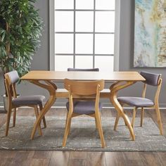 a dining room table with four chairs and a potted plant in the corner next to it