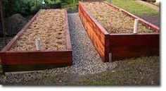 two wooden raised garden beds sitting on top of gravel