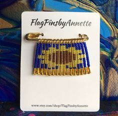 a gold and blue beaded bracelet on a white card with the words flag pins by annette