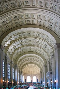 the interior of a library with many bookshelves and people sitting at tables in it