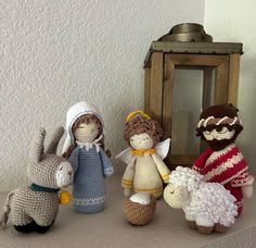 three crocheted stuffed animals sitting on top of a table next to a lantern