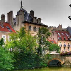 an old bridge over a small river in front of some buildings