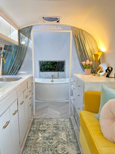 the interior of an airplane bathroom with sink, tub and yellow couch in front of it