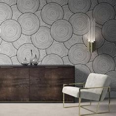 a room with a chair, table and wallpaper on the walls that has circles painted on it