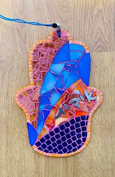 an ornament made out of stained glass on a wooden surface with a blue string