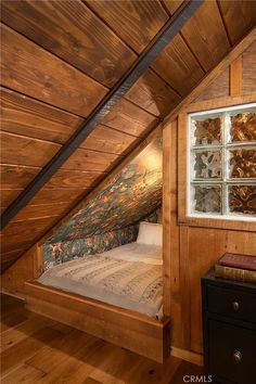 an attic bedroom with wood paneling and glass windows on the wall above the bed