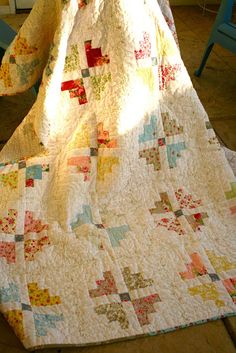 a quilted blanket sitting on top of a wooden floor next to a chair and table