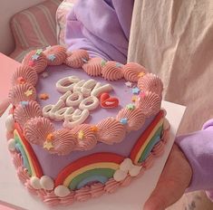 a heart shaped cake with the word love spelled on it and rainbows in the frosting