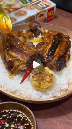 a plate with rice, meat and sauce on it next to a box of food