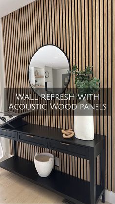 a black table with a mirror and vase on it in front of a striped wall