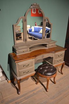 an antique vanity with mirror and stool in a room that has hardwood floors, blue walls, and wood flooring