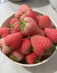 a white bowl filled with lots of ripe strawberries