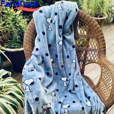 a blanket that is on top of a wicker chair next to potted plants