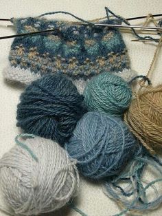 several balls of yarn and knitting needles on a table