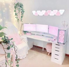 a white desk topped with two computer monitors next to a potted plant in a room